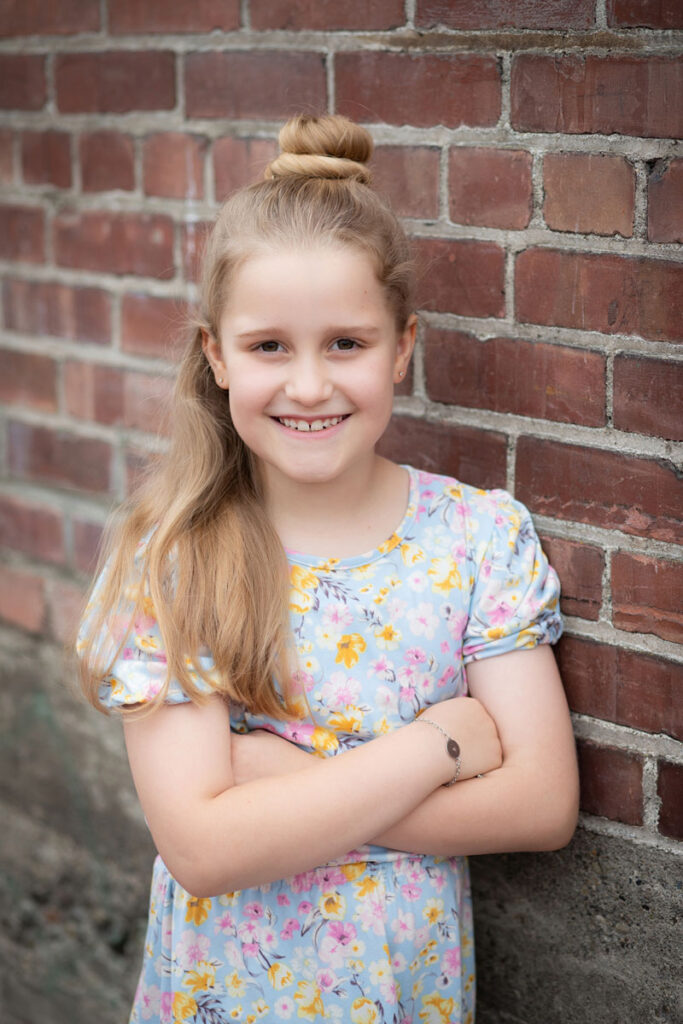 girl leaning on brick wall smiling