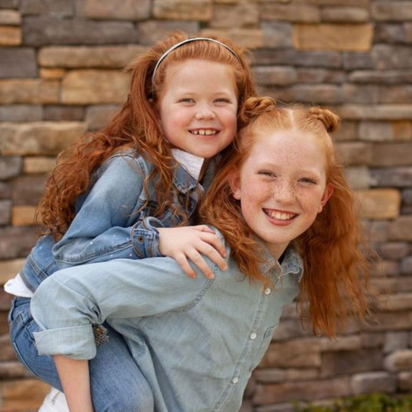 one sister giving another a piggy back ride